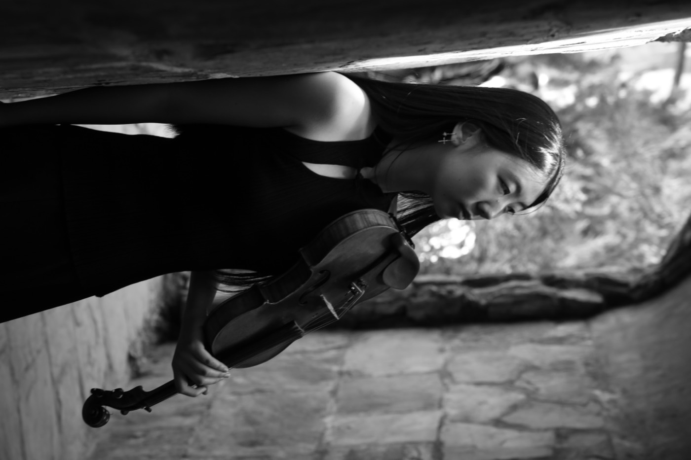 Calina in a stone archway, holding her violin