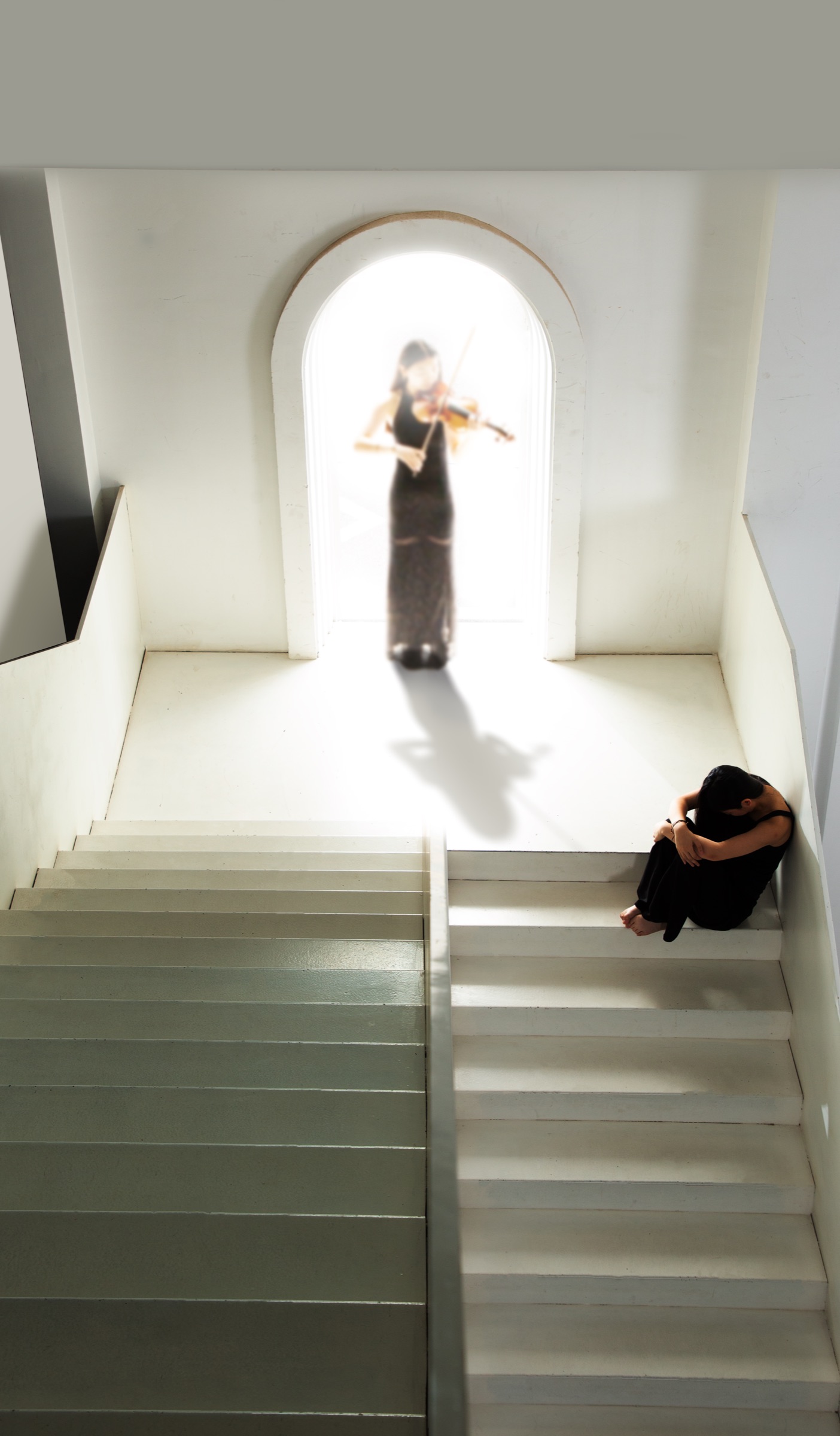 Calina sits crouched on the stairs, head on her knees, below the violinist in the arch.